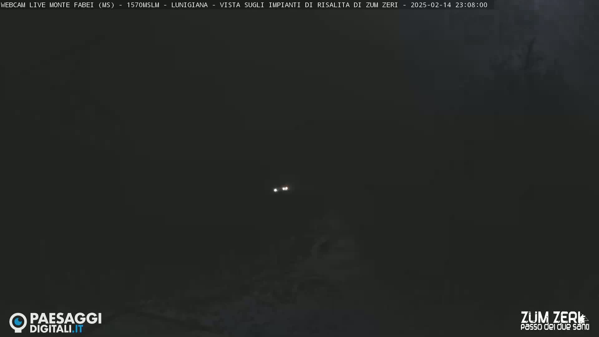 Two small, bright lights are visible in the distance on a very dark, nighttime landscape.