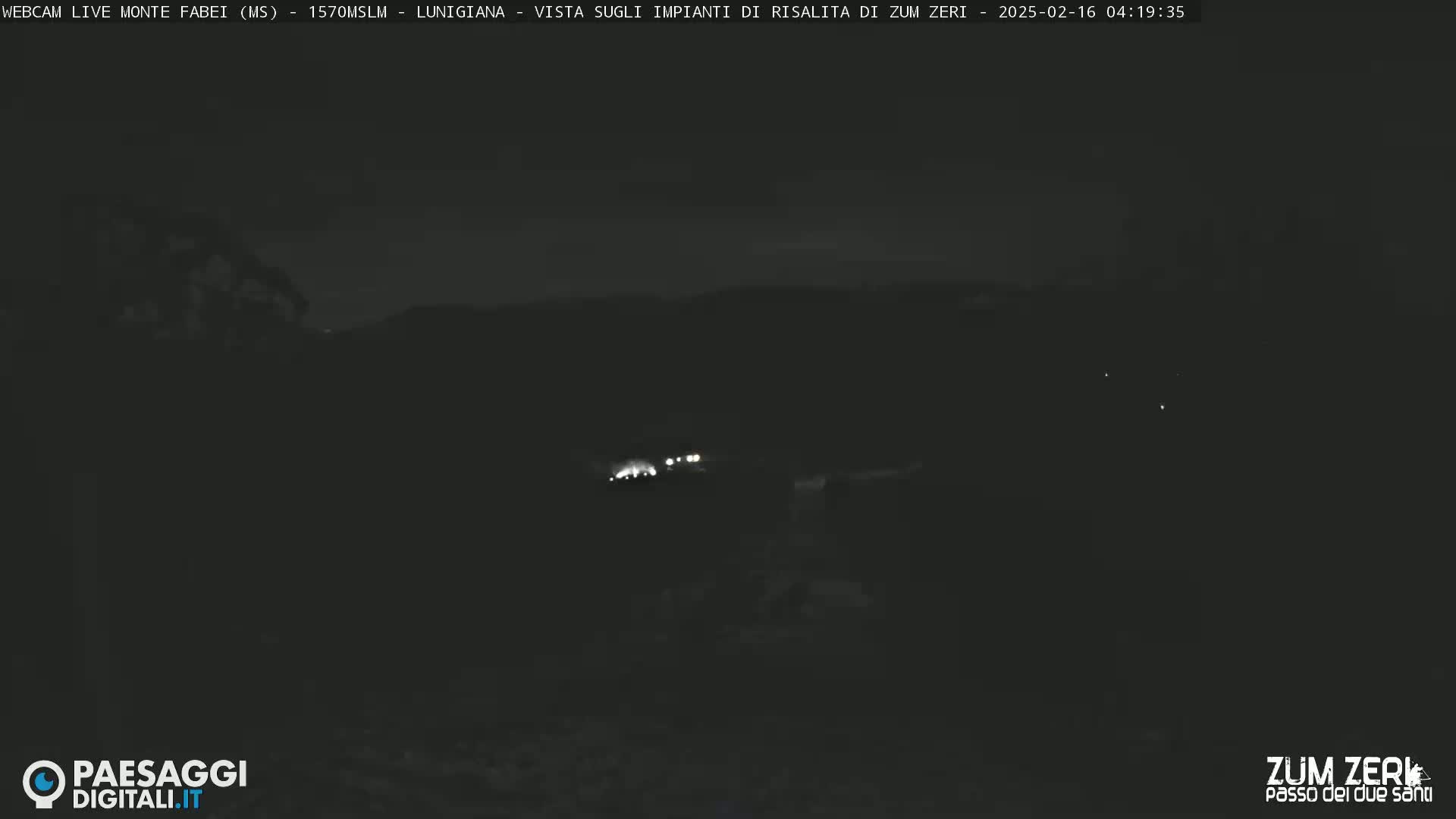 A nighttime, low-light view of dimly lit hills and a few distant lights.