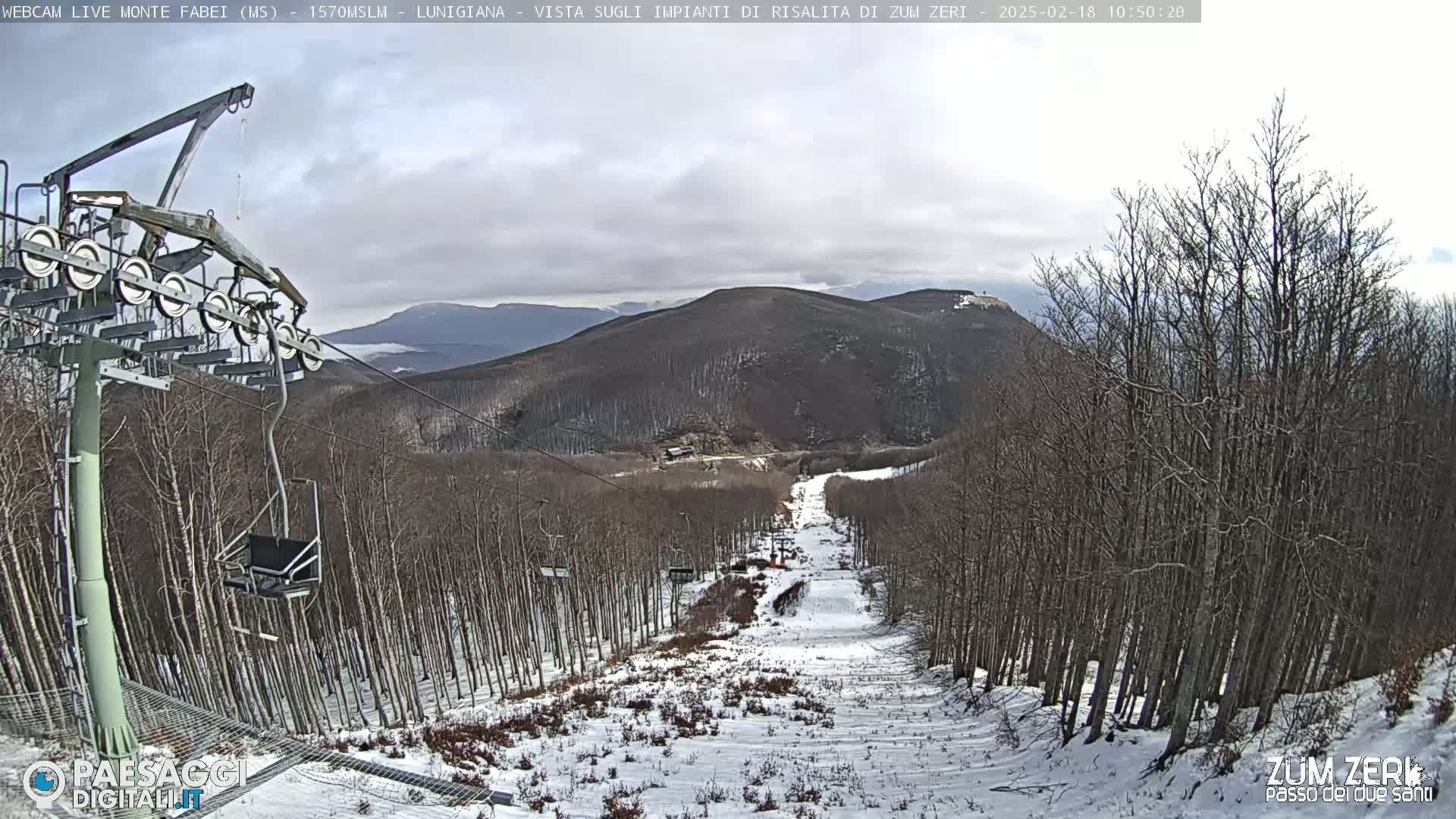 A chairlift and snowy ski slope are visible, surrounded by leafless trees under an overcast sky.