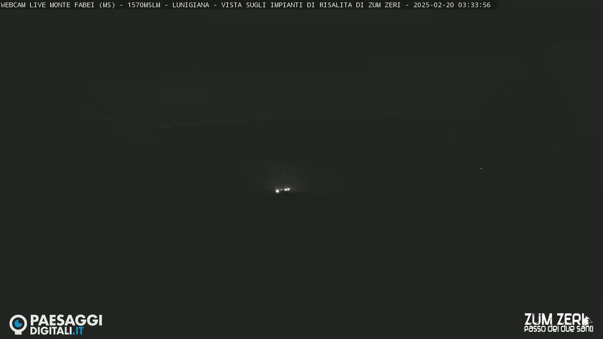A dark, nighttime scene shows a few faint lights in the distance.