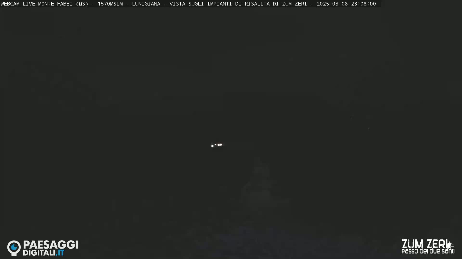 A dark, nighttime scene shows a distant pair of headlights in the middle of the frame.