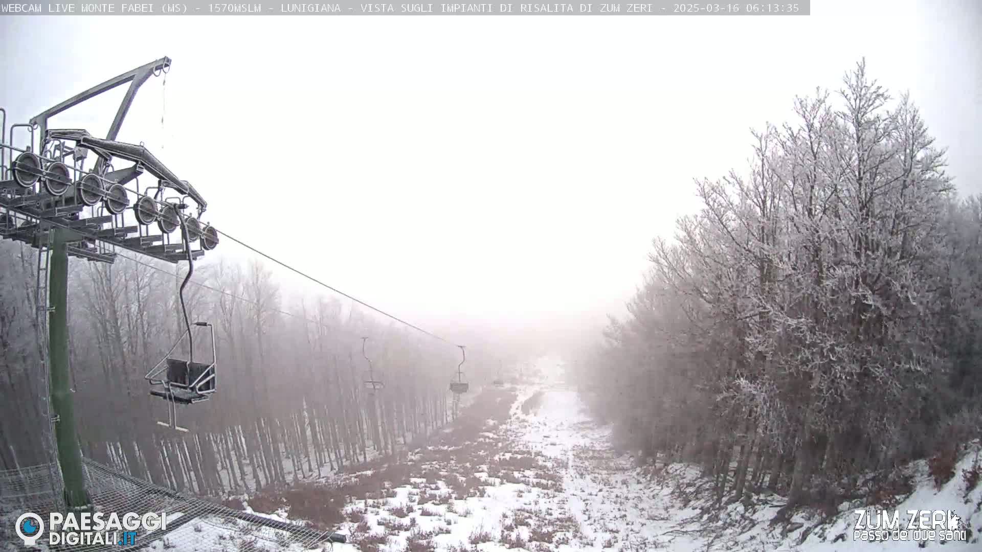 A chairlift ascends a snowy, foggy mountain slope lined with frost-covered trees.