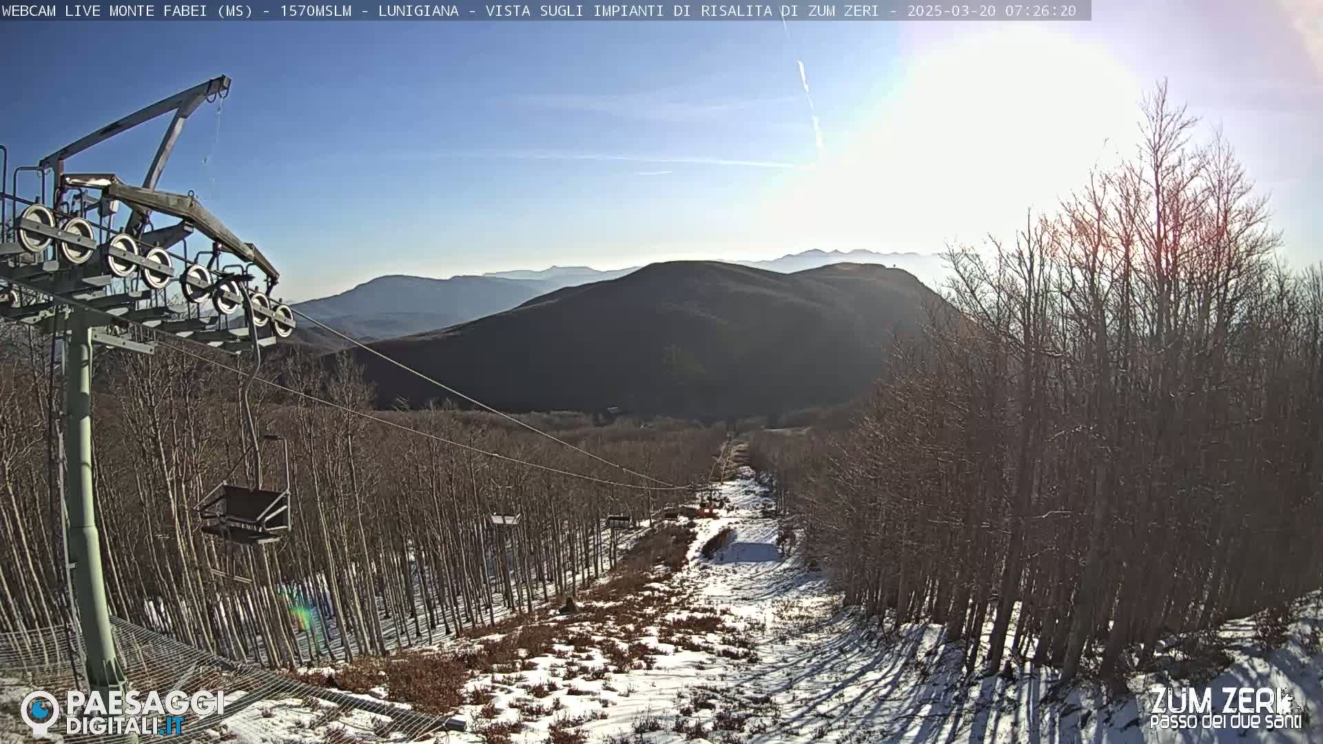 A chairlift ascends a snowy mountainside under a clear, sunny sky.