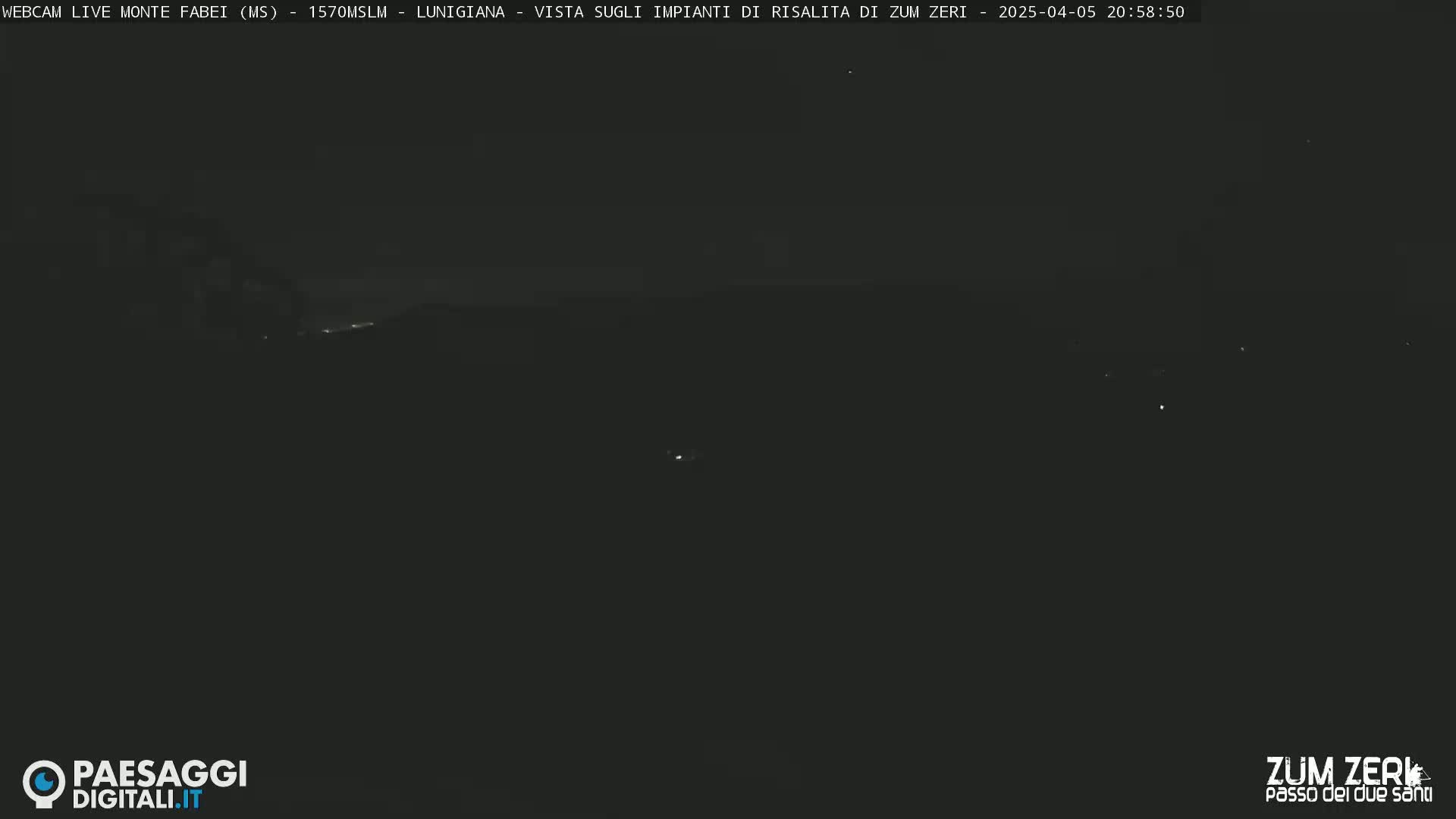 A dark, nighttime view of a distant landscape with a few faint lights visible.
