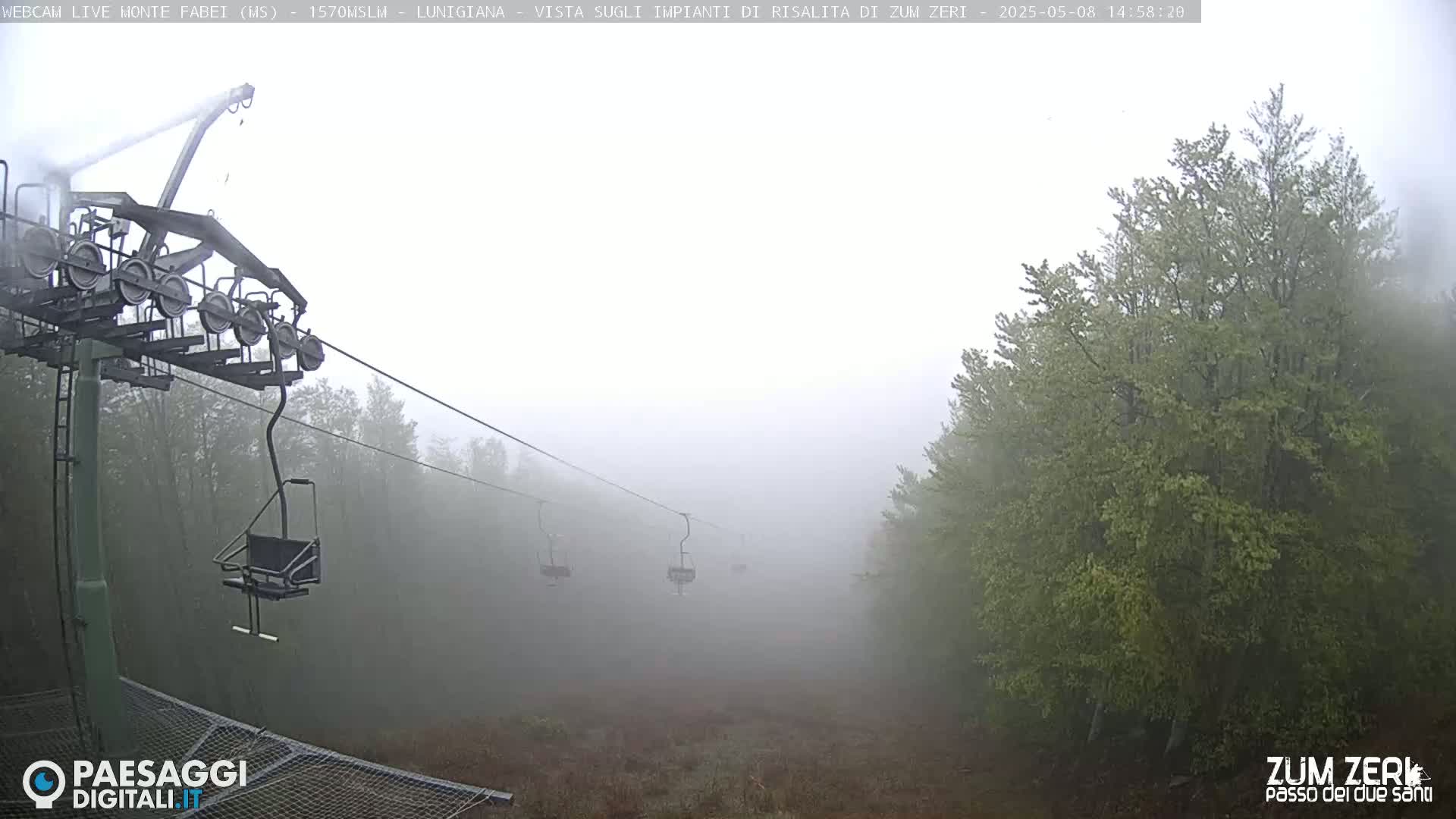 A foggy mountain scene shows a chairlift with empty chairs extending into a misty forest.