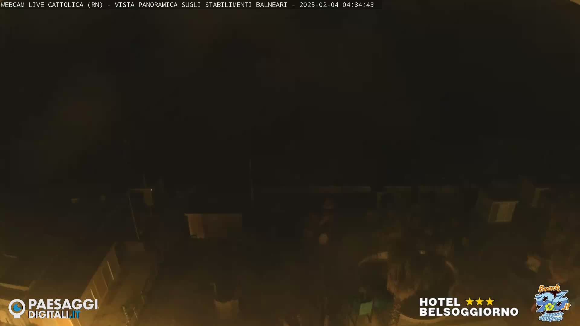 A nighttime, dark view of buildings and a possibly beach area under a mostly clear sky.