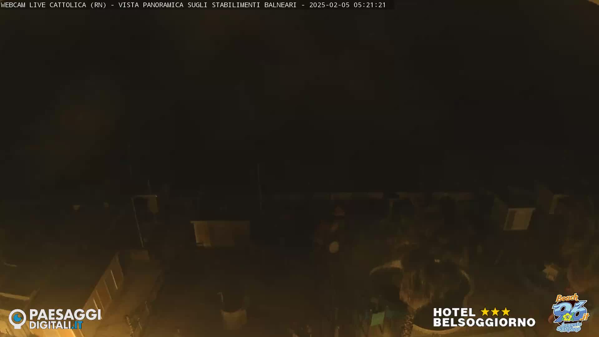 A nighttime, low-light view of a dark area showing the tops of buildings and a possibly a pool or similar structure.