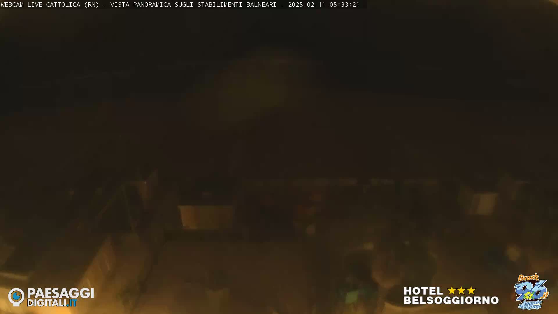 A dark, nighttime view of a beach area with dimly lit structures.