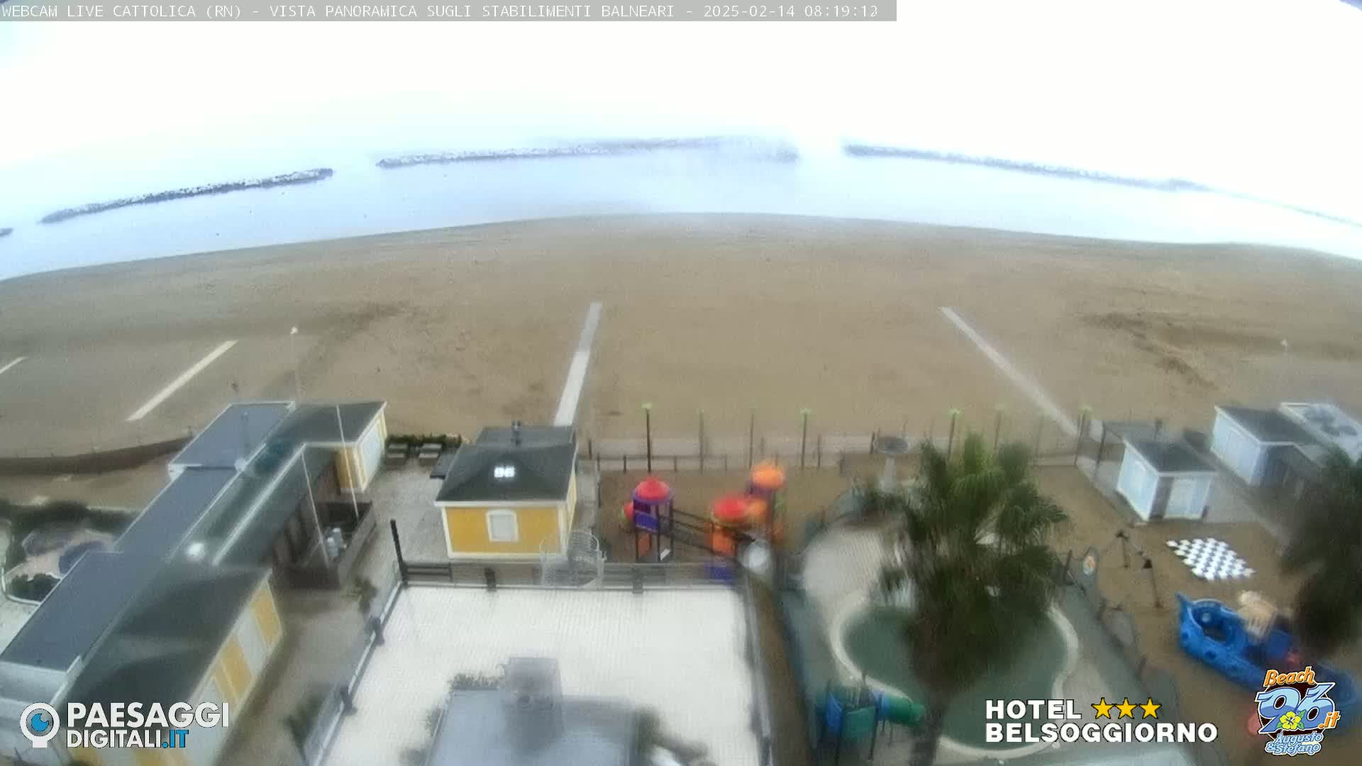 An overcast day at a beach with a playground and buildings visible, viewed from above.
