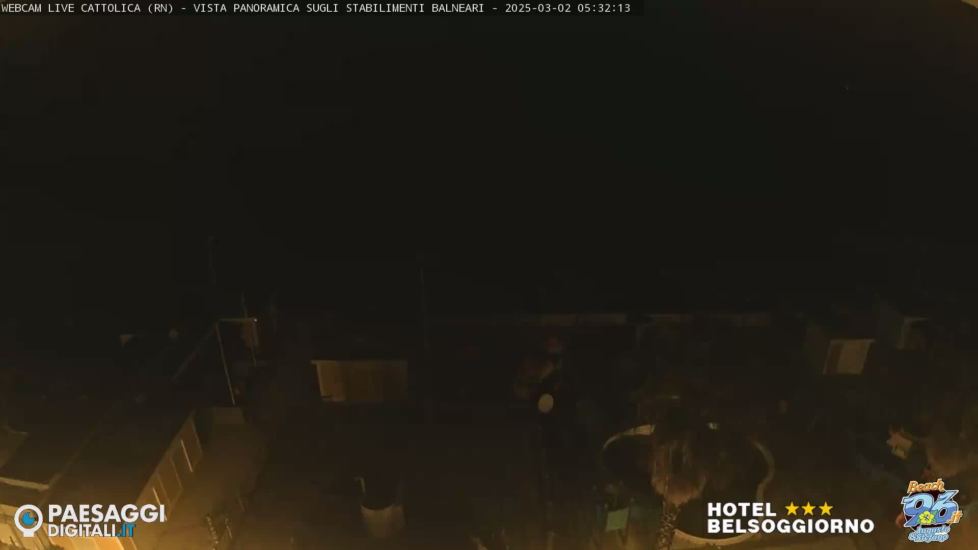 A nighttime, dark view overlooking a dimly lit outdoor area, possibly a beachside establishment.