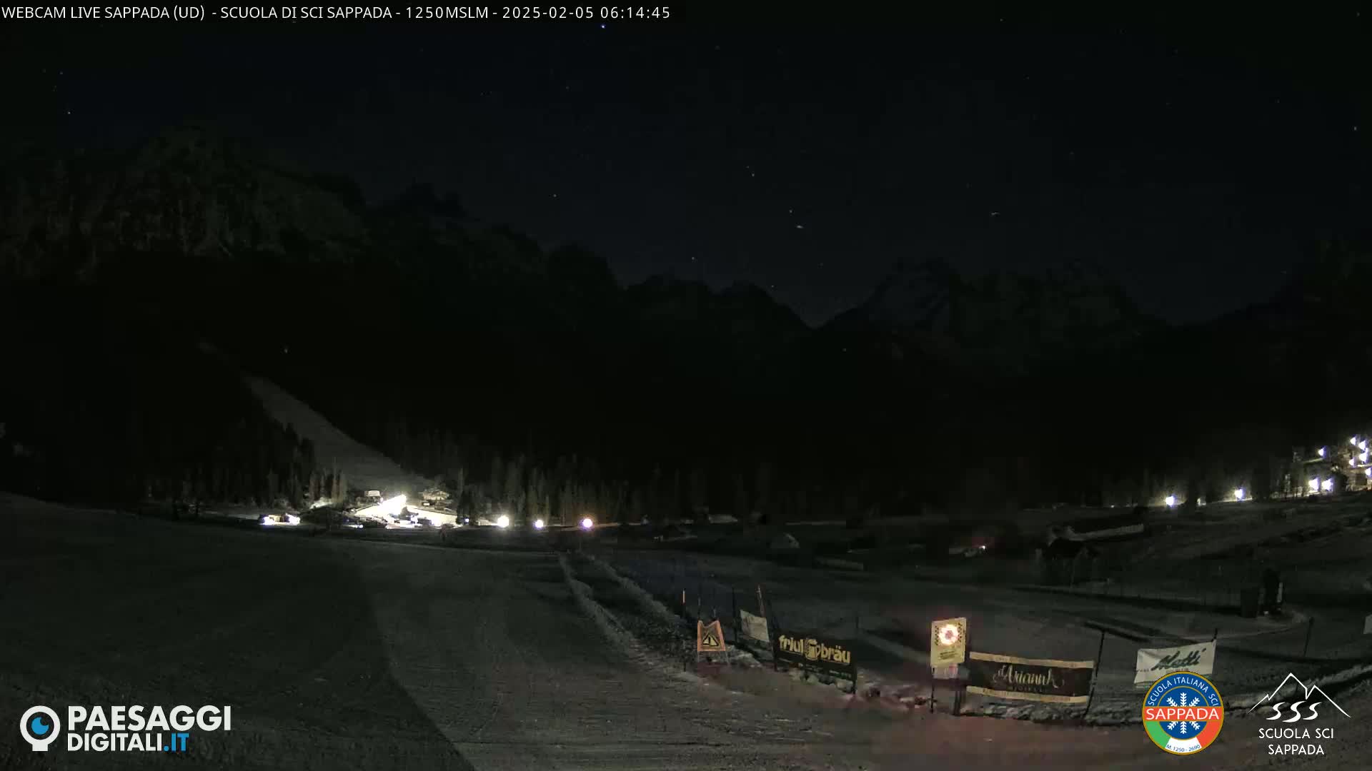 A nighttime view of a snow-covered ski slope with a mountain in the background under a clear, starlit sky.
