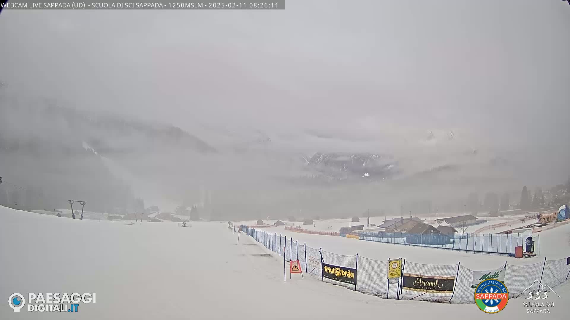 A snow-covered ski slope is visible in the foreground, with foggy mountains in the background under overcast skies.