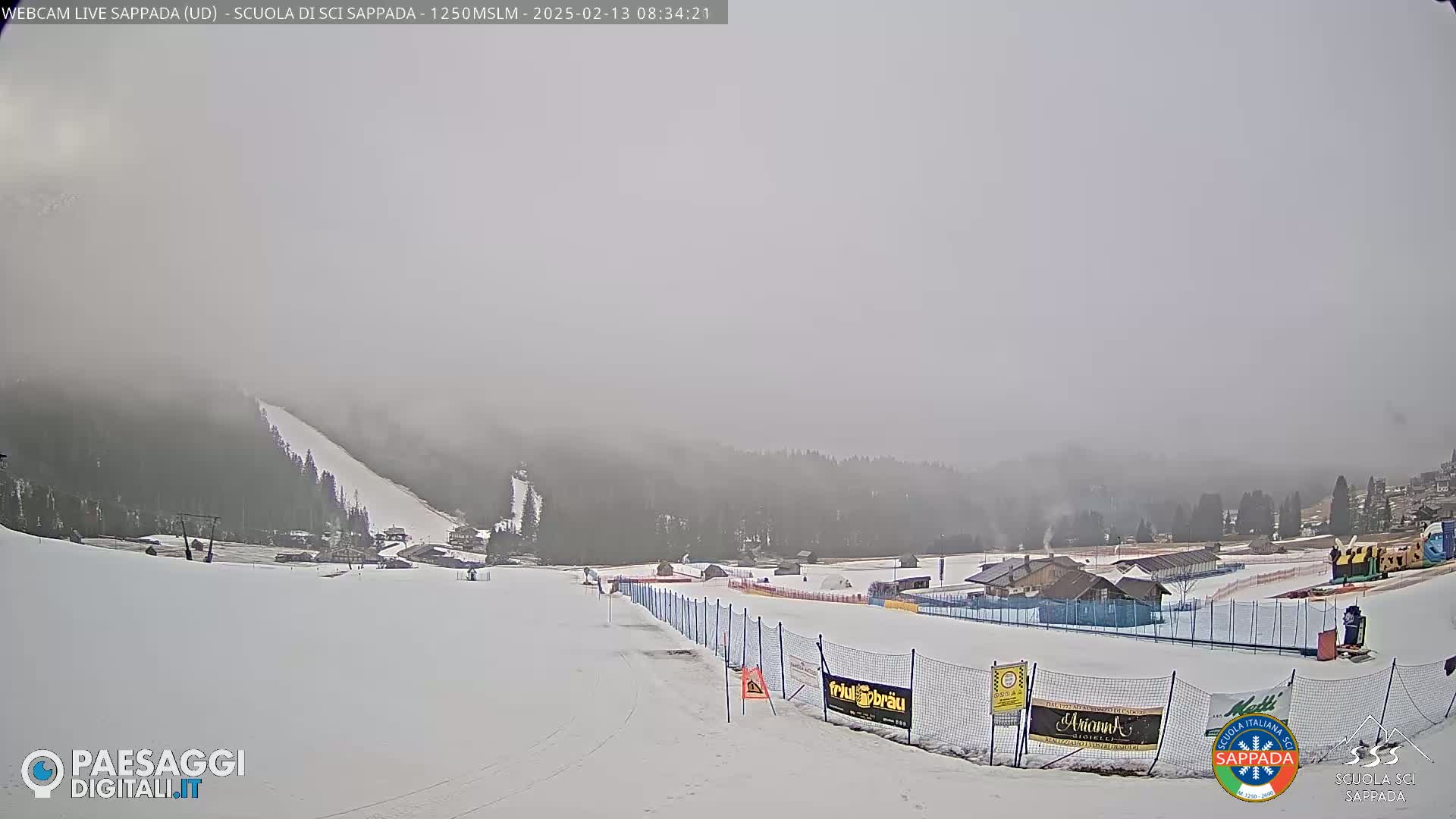 A snow-covered ski slope and surrounding buildings are visible in foggy weather conditions.