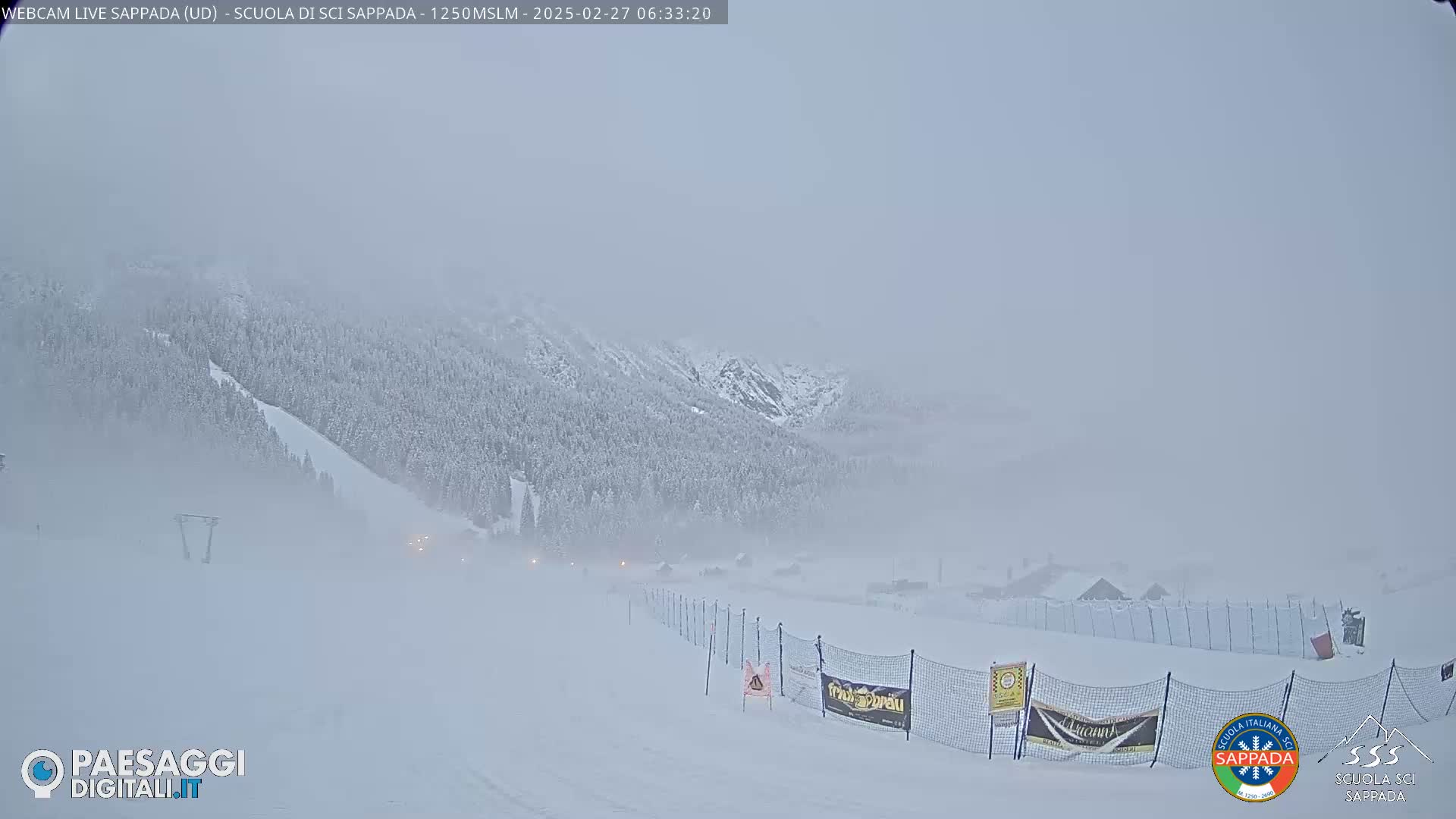 A snow-covered ski slope and mountain range are obscured by heavy fog.