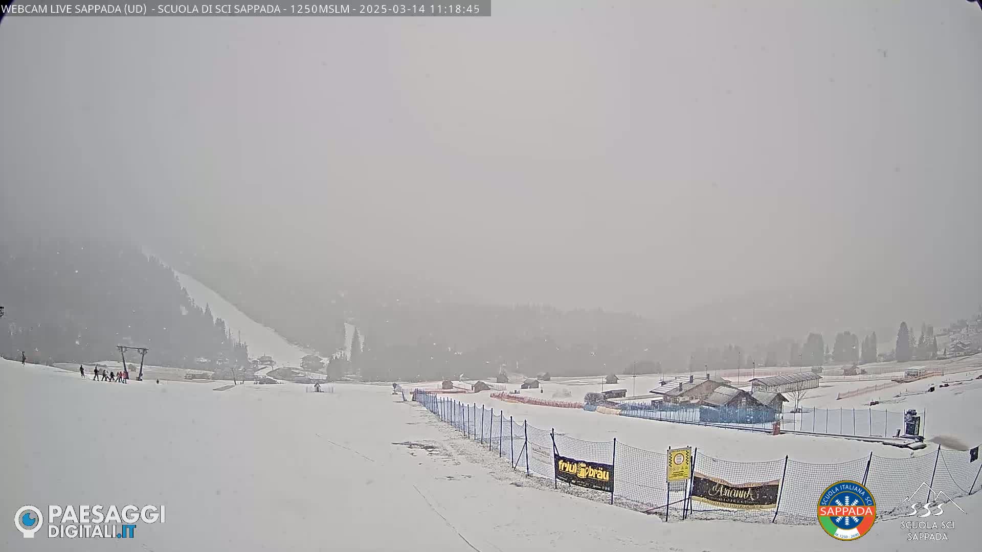 A snowy, hazy landscape shows a ski slope with several people, a ski lift, and buildings in the distance.