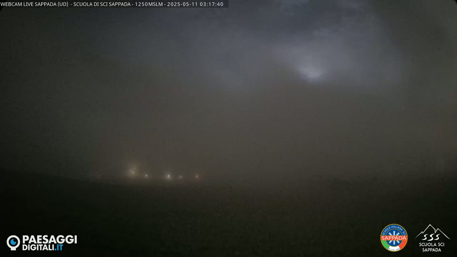 A hazy, dark landscape is visible at night, with a few distant lights barely perceptible through the heavy fog or dust.