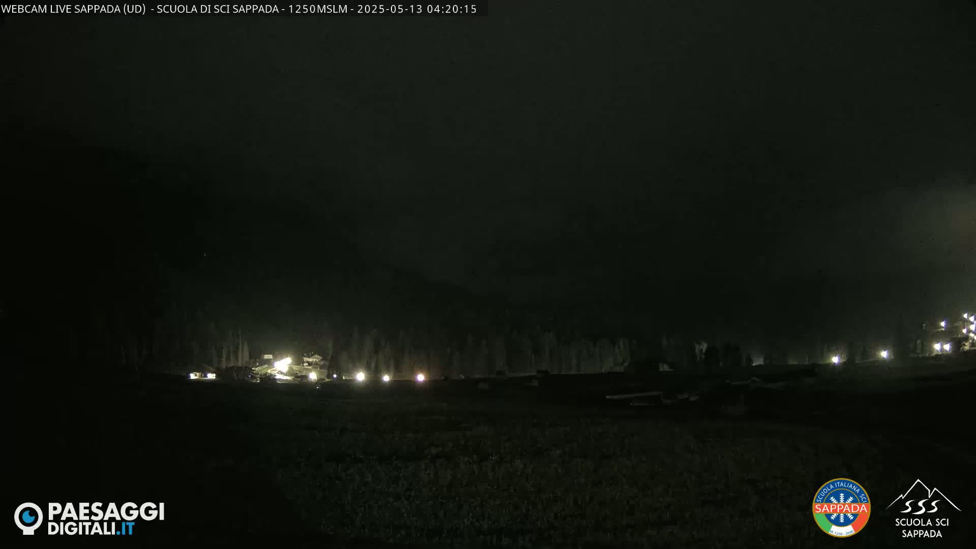 A dark nighttime scene shows a row of dimly lit objects against a foggy or hazy background.