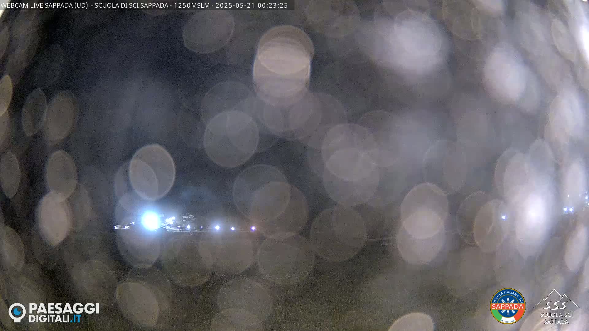 A blurry nighttime view of lights in the distance, obscured by rain or condensation on a window.