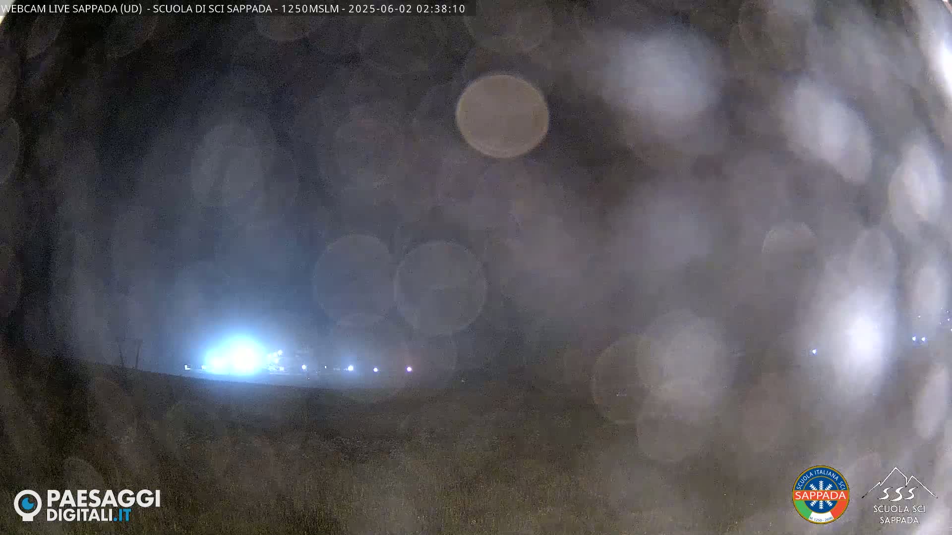A blurry nighttime scene shows a distant line of lights through a hazy, possibly foggy atmosphere.