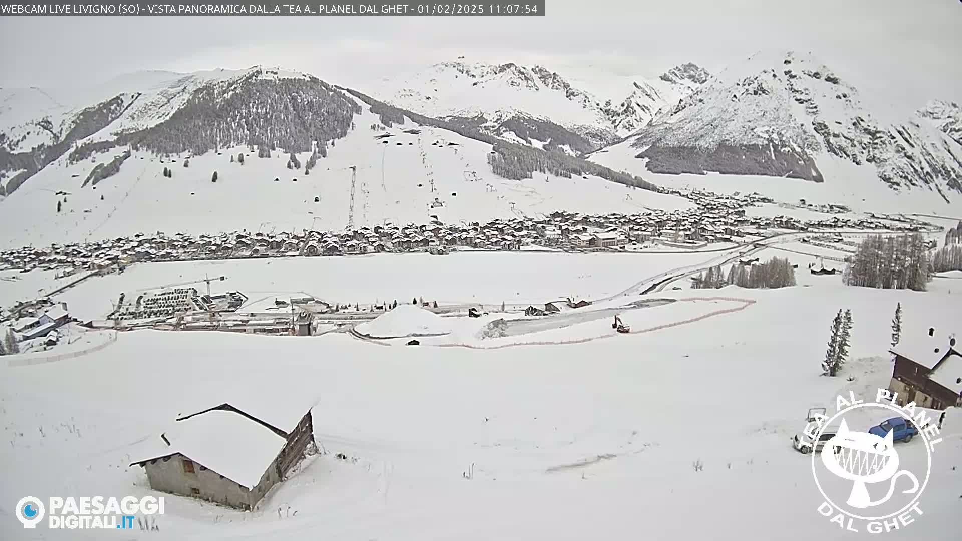 A snow-covered mountain village is seen from a high vantage point, with overcast skies and snow-covered slopes and buildings.