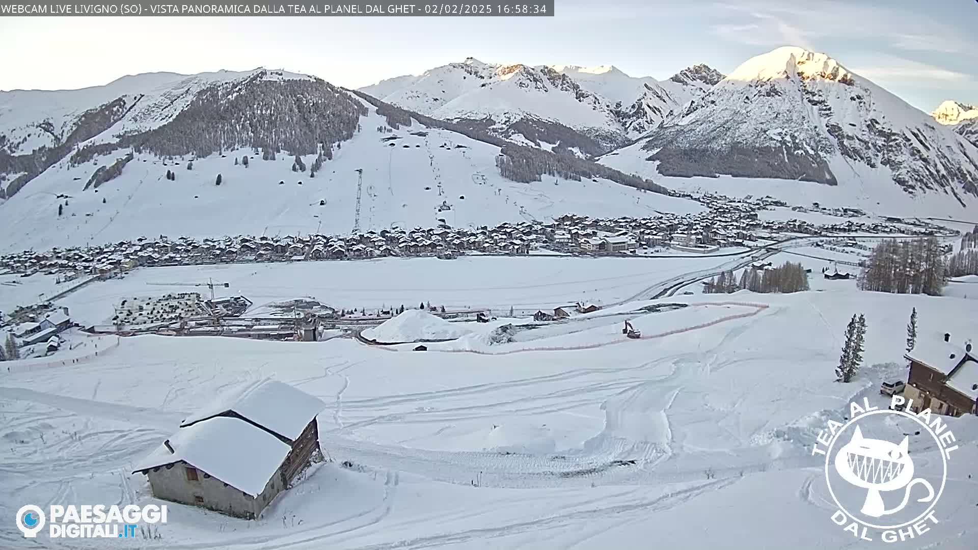 A snow-covered mountain village nestled in a valley surrounded by snow-capped mountains under a clear sky.