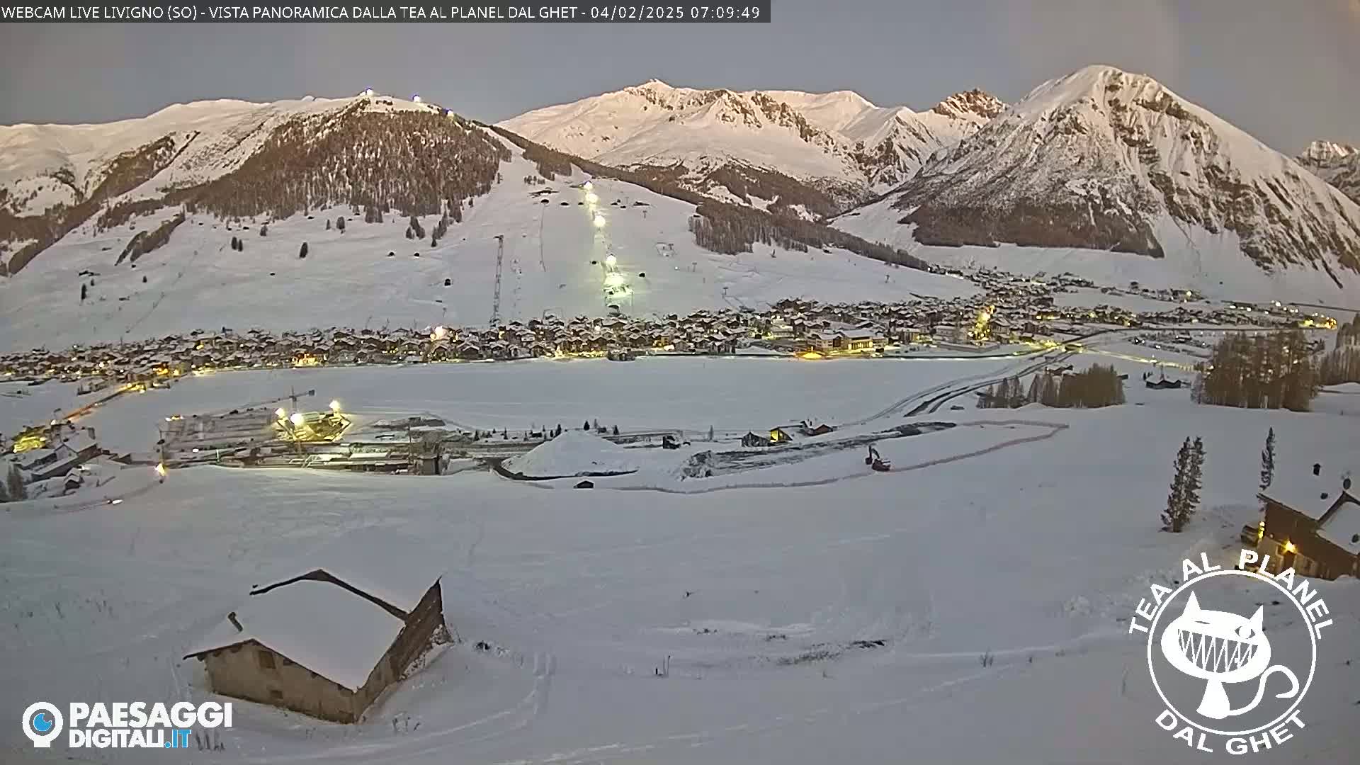 A snow-covered village nestled in a valley between snow-capped mountains at dawn.
