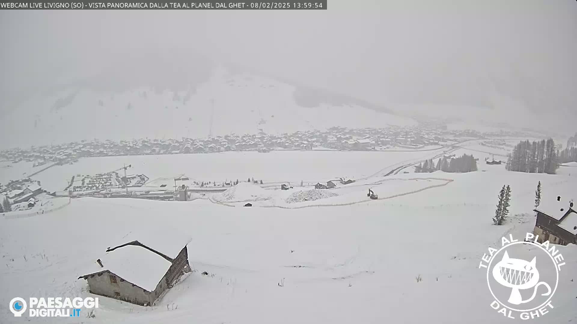A snow-covered landscape with a village in the distance is seen on an overcast day.