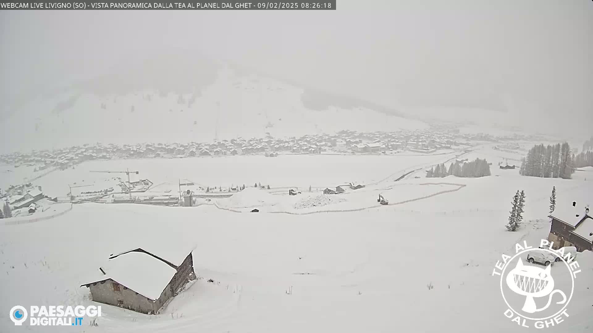 A snow-covered village and surrounding landscape are visible under heavy snowfall.