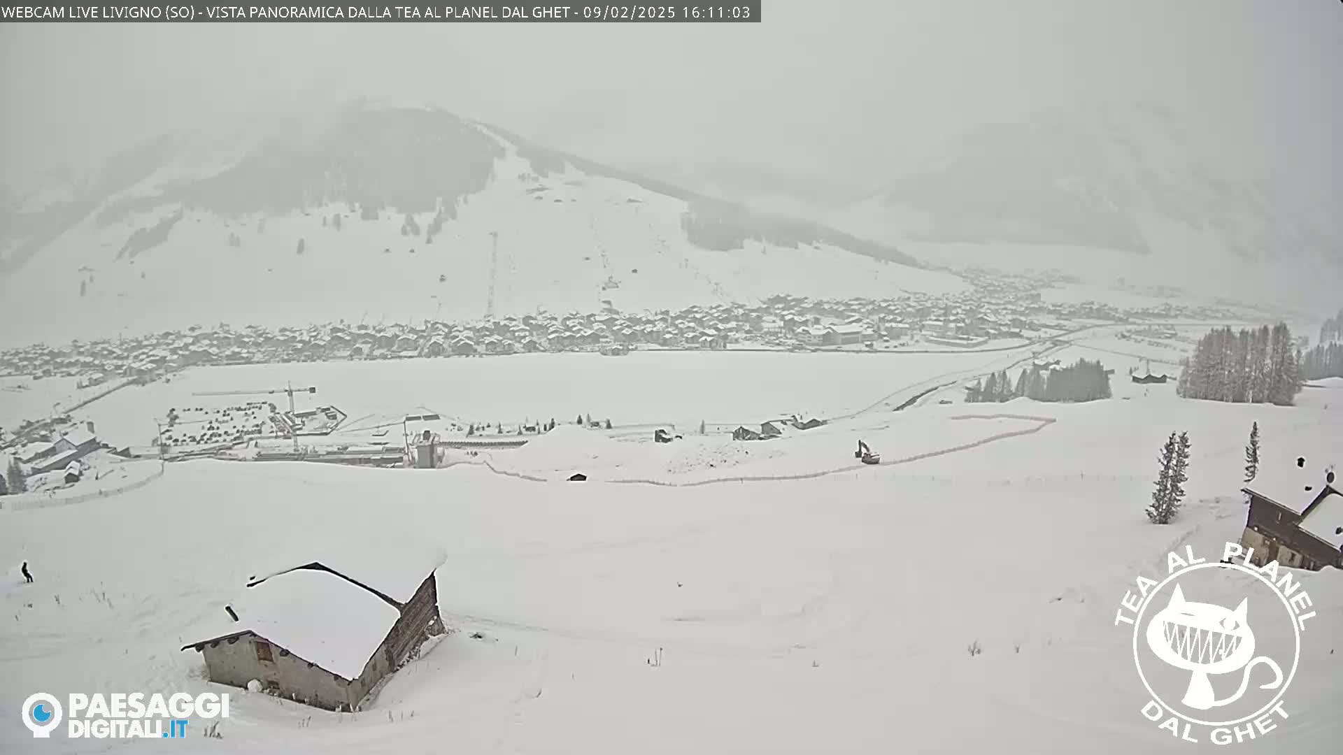 A snow-covered village and ski slope are visible under heavy snowfall.