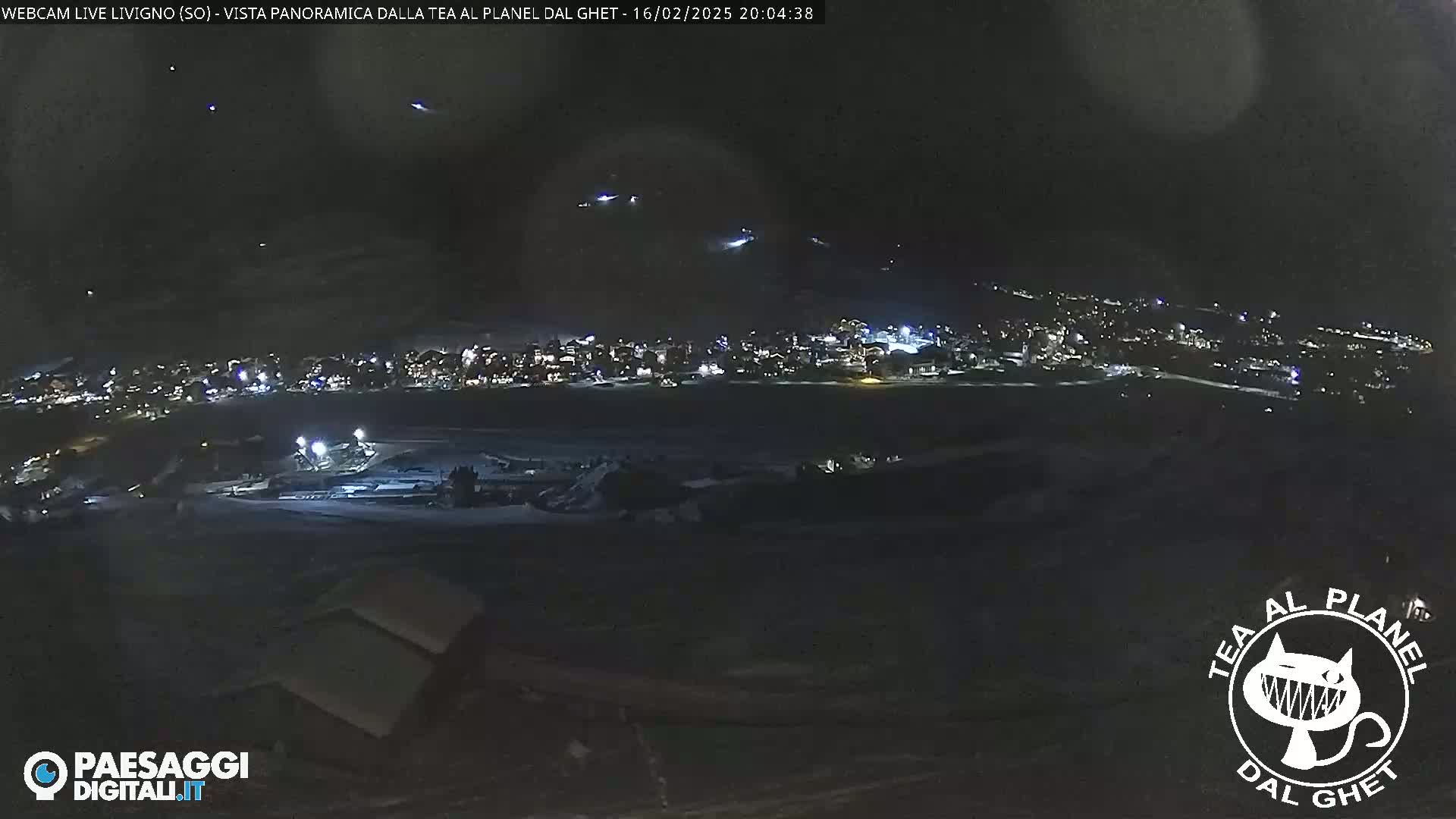 A nighttime, panoramic view of a snow-covered town illuminated by lights under a dark sky.