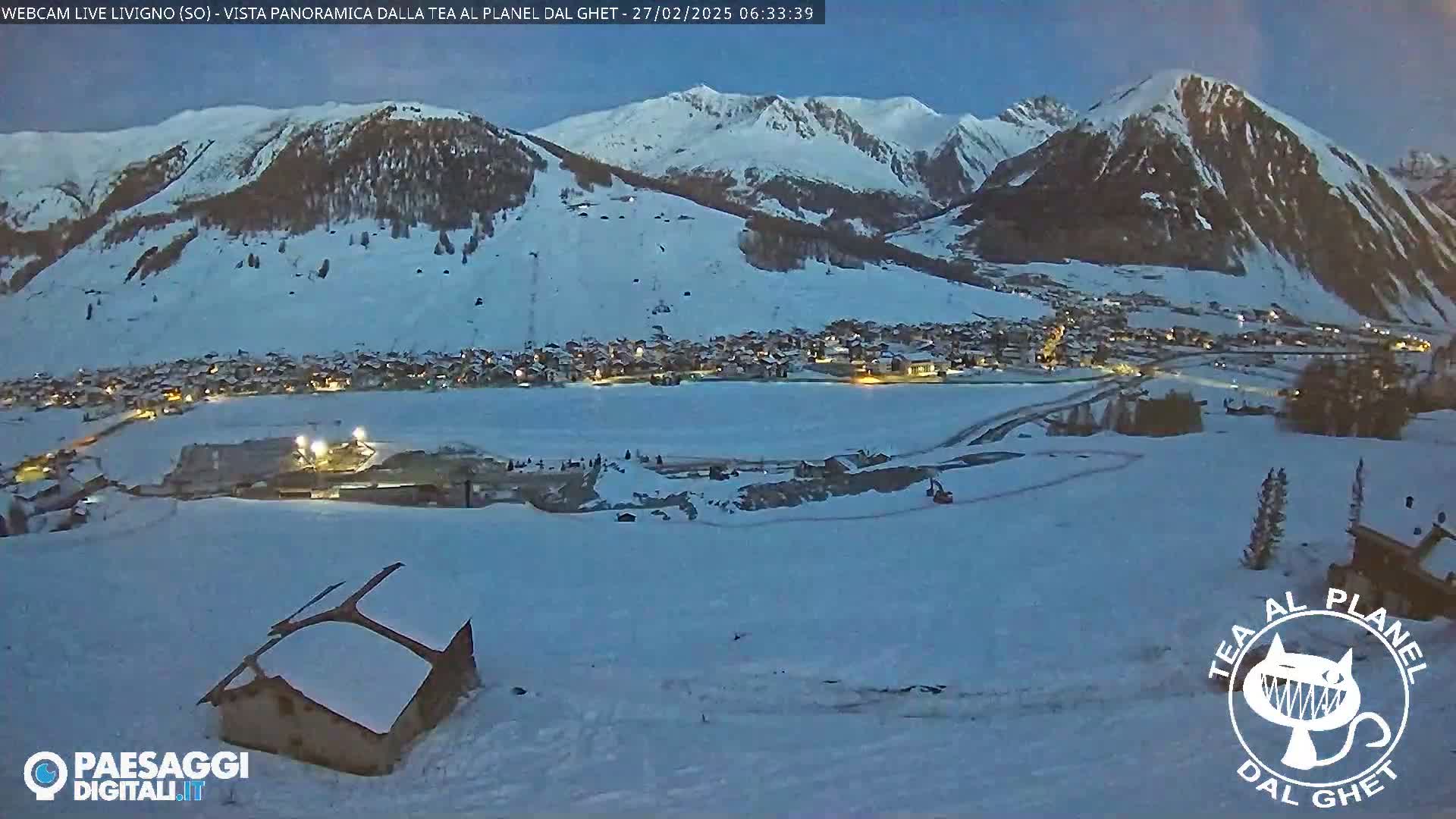 A snow-covered village nestled in a valley between snow-capped mountains at twilight.