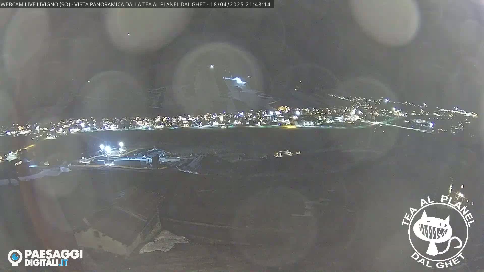 A nighttime, panoramic view of a snow-covered town illuminated by lights, with a dark sky.