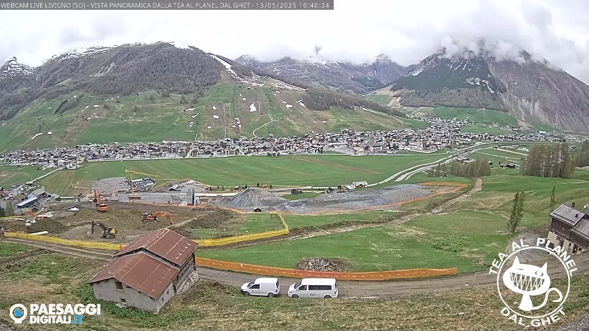 A mountain town nestled in a valley, with construction visible in the foreground and overcast skies.