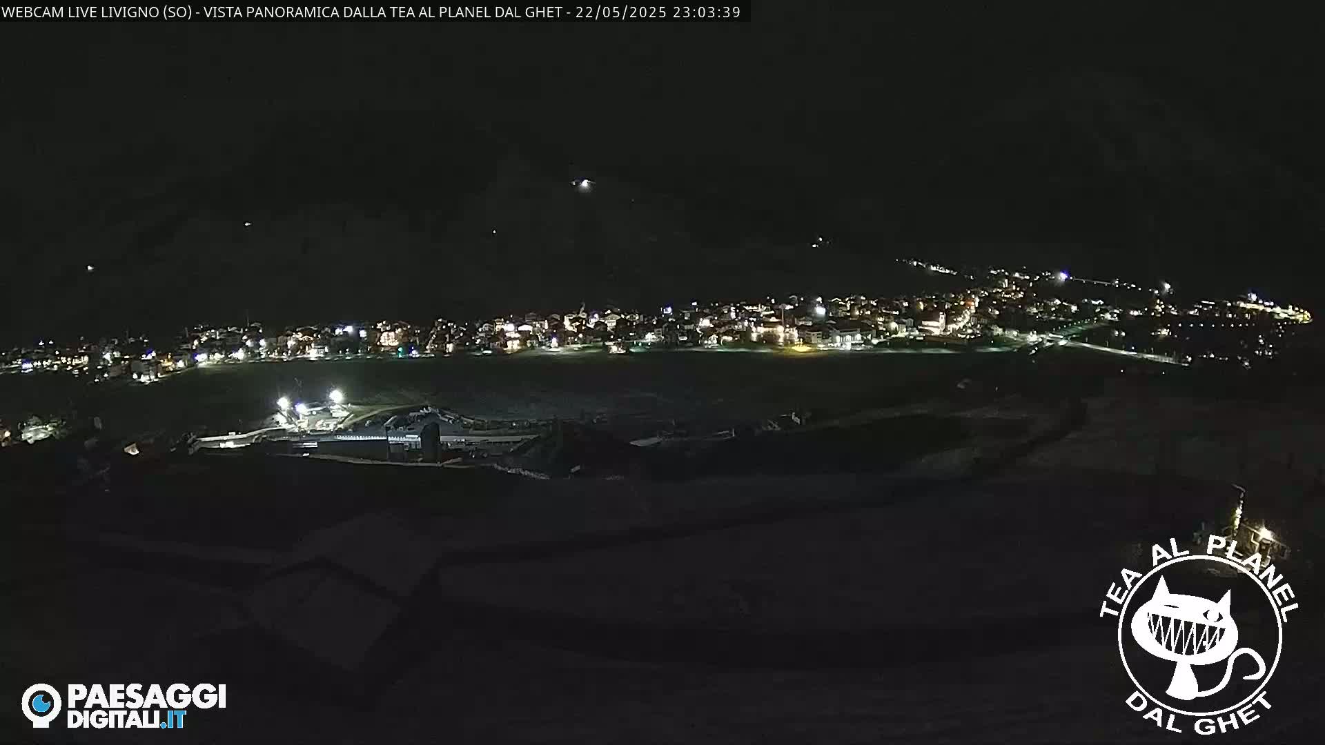 A nighttime, panoramic view of a snow-covered town illuminated by lights, under a clear, dark sky.