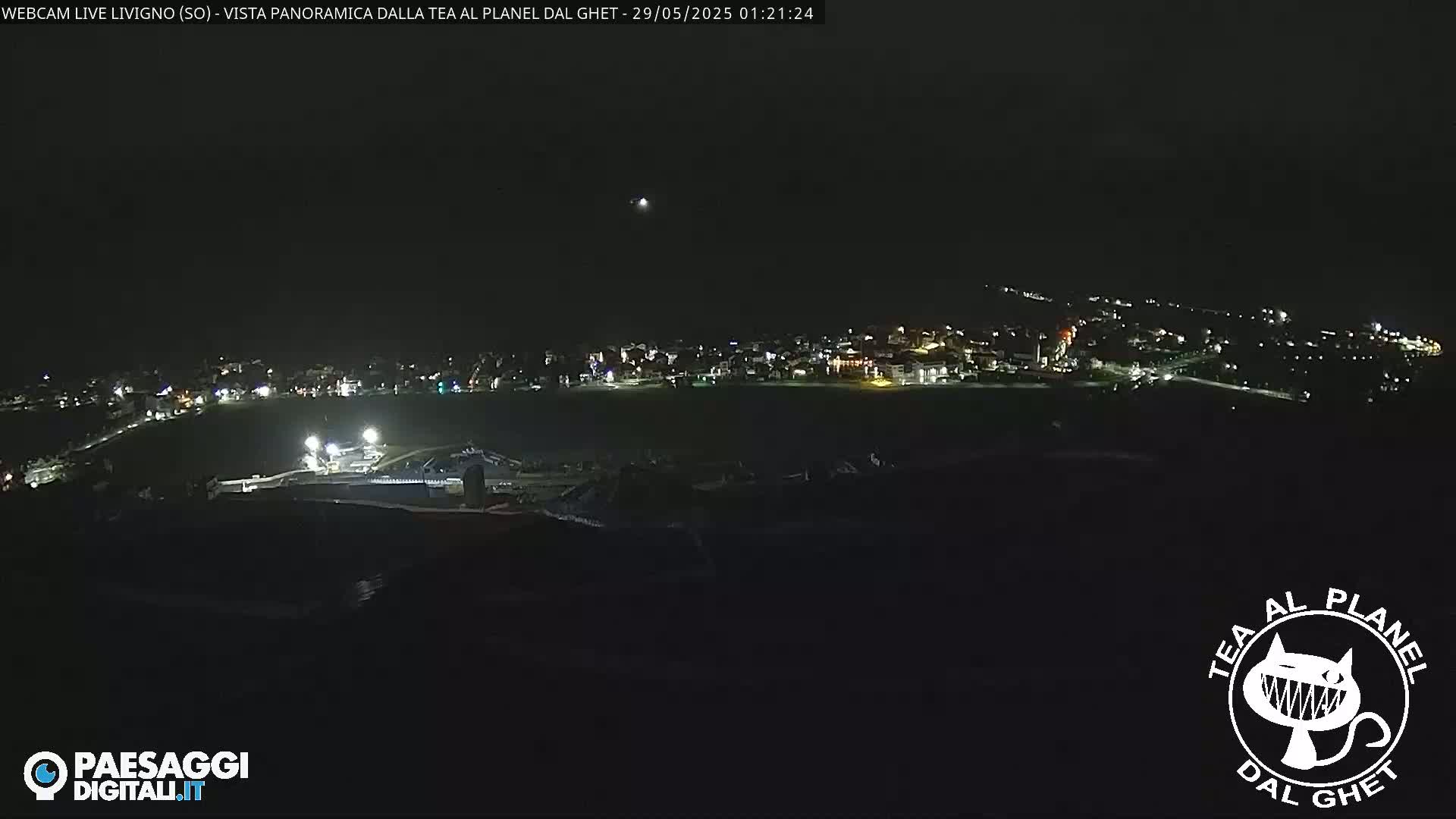 A nighttime, panoramic view of a town illuminated by scattered lights, under a clear, dark sky.