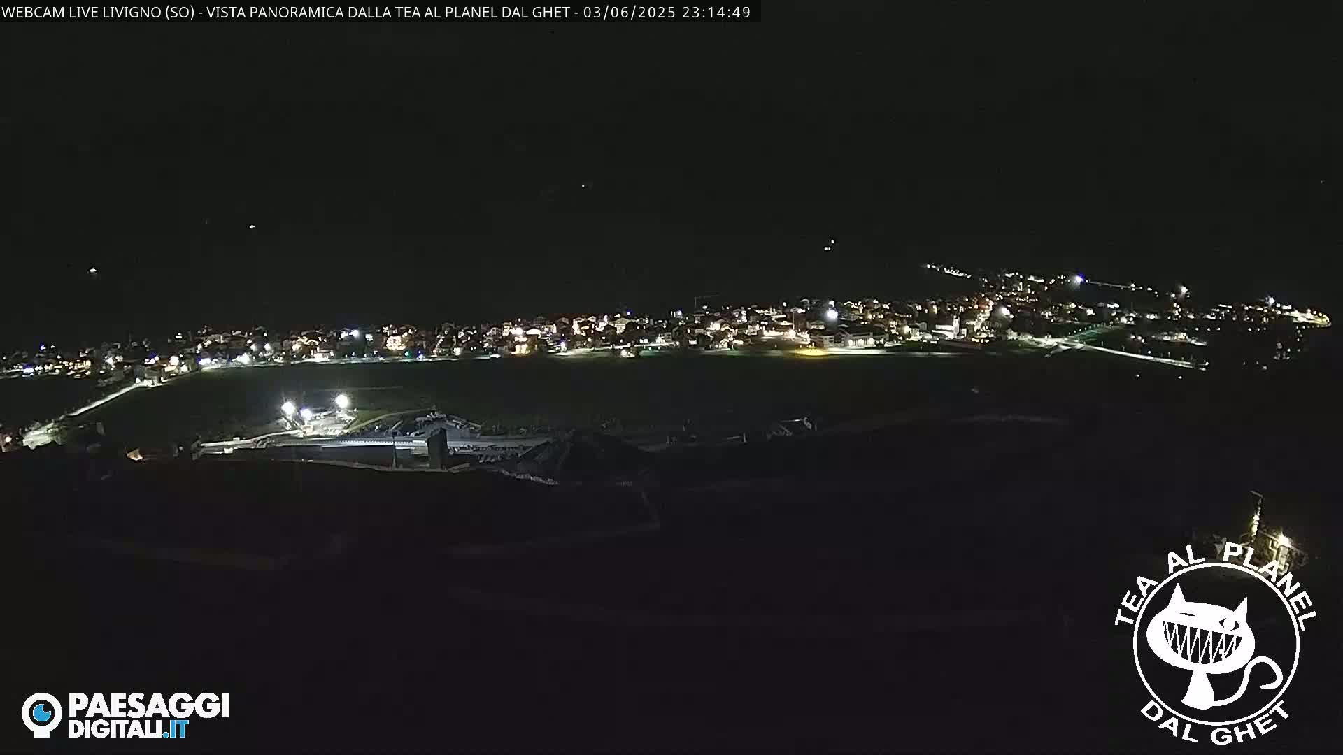 A nighttime, high-angle view shows a small town illuminated against a dark sky.