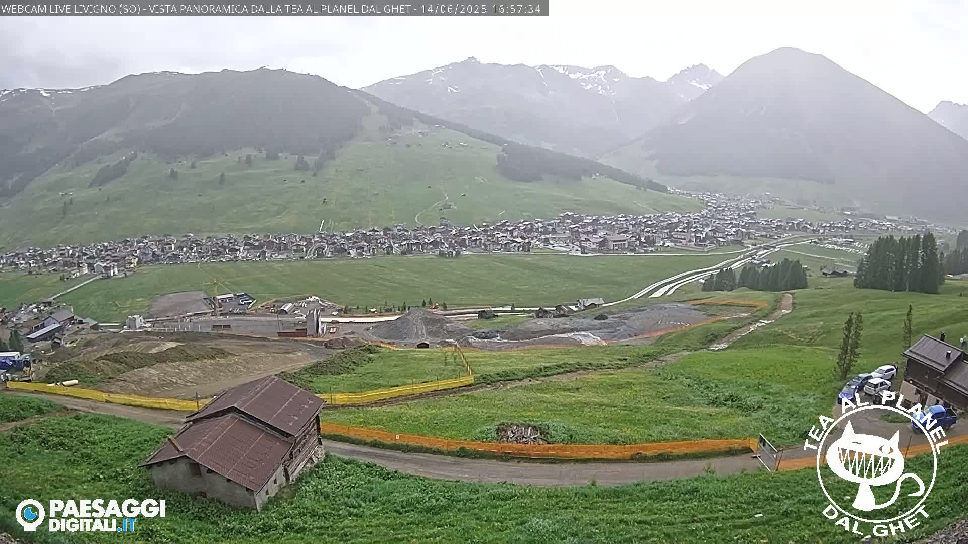 A misty mountain landscape shows a town nestled in a valley below, with construction visible in the foreground, and a small building near the bottom.