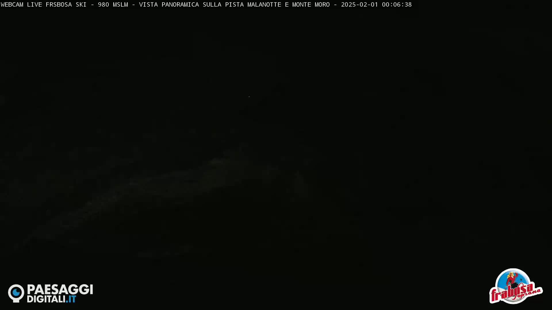 A dark, nighttime panoramic view of a snowy landscape with faint illumination in the distance.