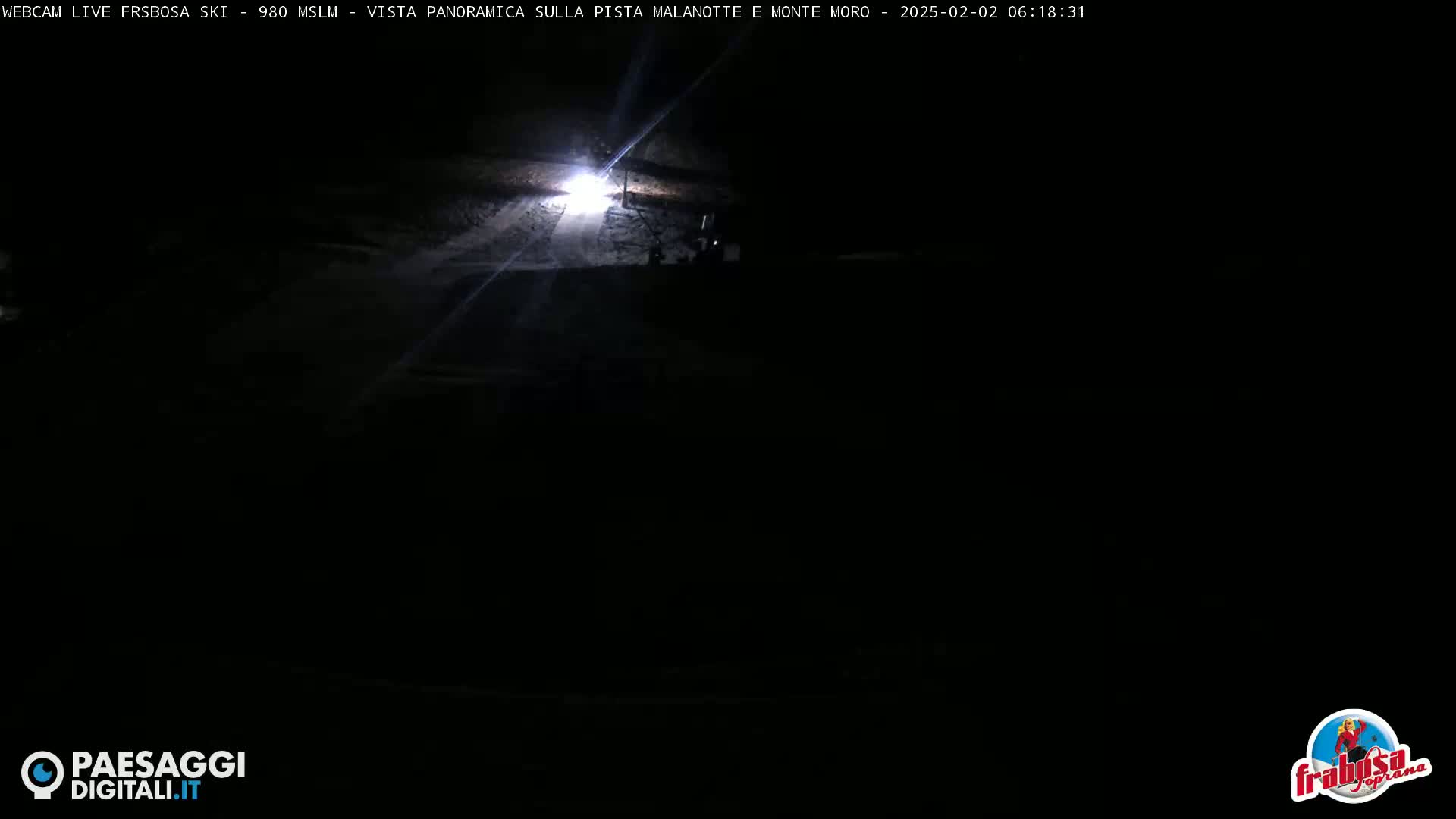 A dark, nighttime scene shows a brightly lit area of what appears to be a road or path.