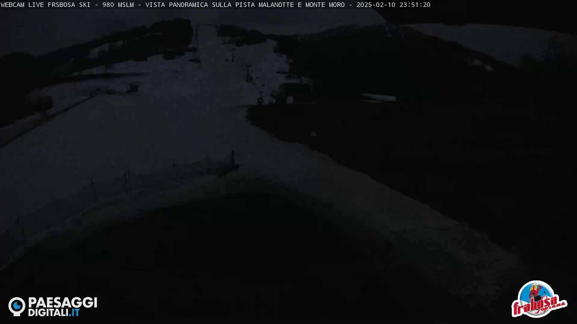 A dark, nighttime view of a snow-covered ski slope.