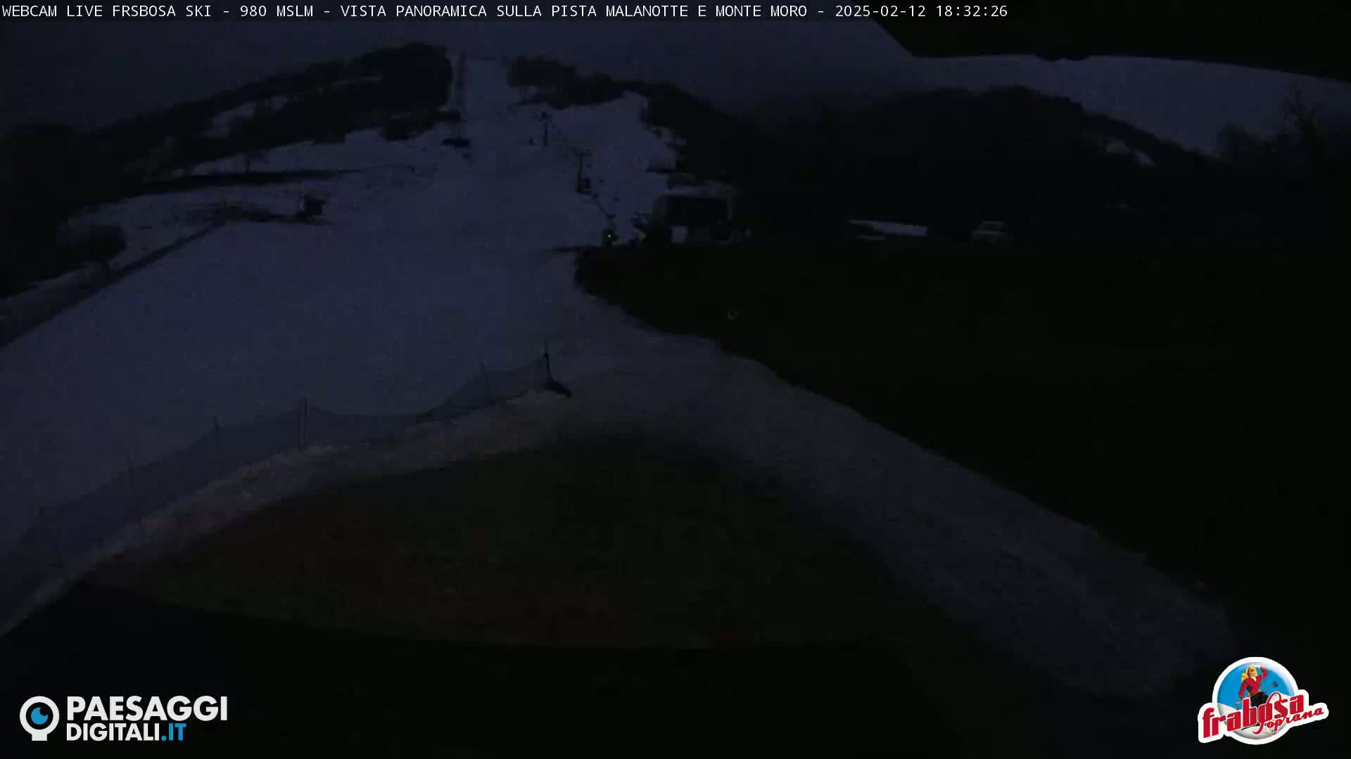 A dark, nighttime view of a snow-covered ski slope with a snow groomer near the bottom.