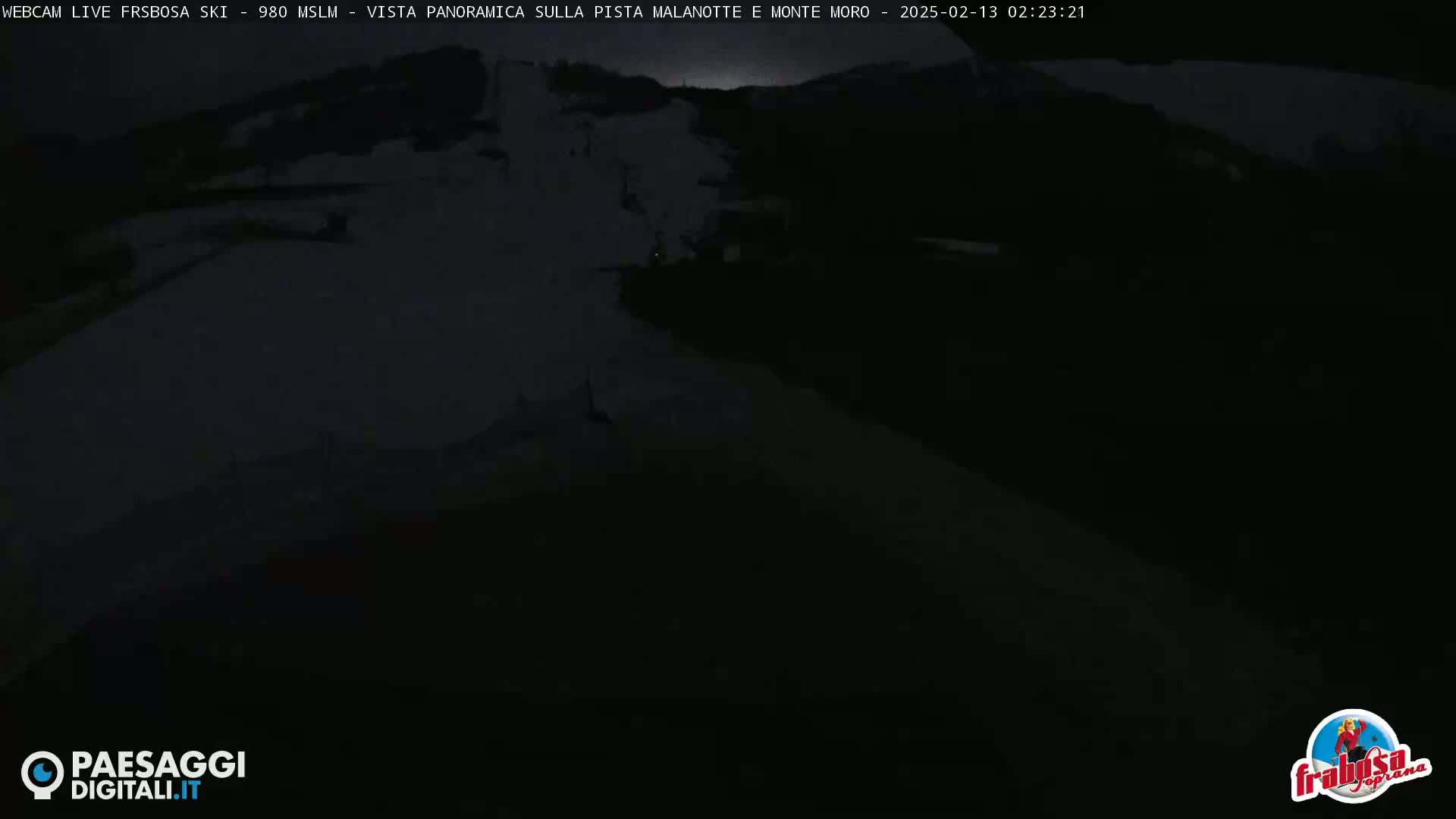 A dark, nighttime view of a snow-covered slope with a machine at the bottom.