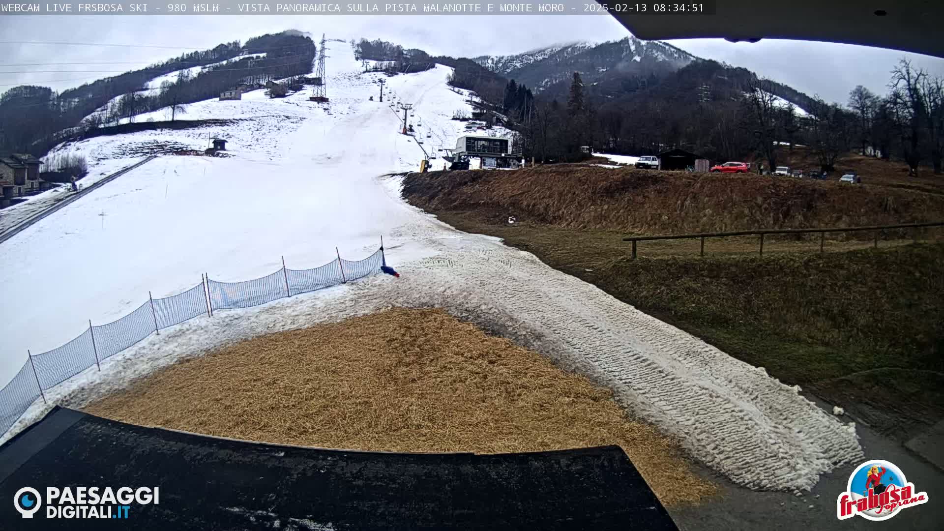 A snow-covered ski slope with a tan-colored area at the bottom, under an overcast sky.