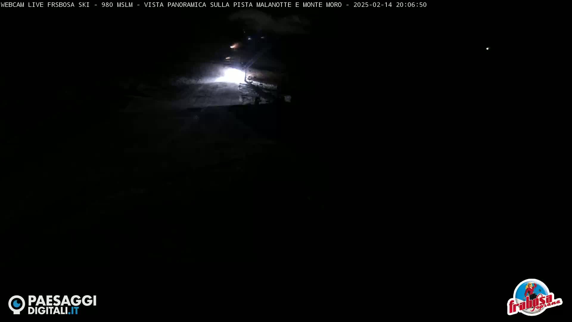 A nighttime, snow-covered road is visible, with a vehicle's headlights illuminating the area.