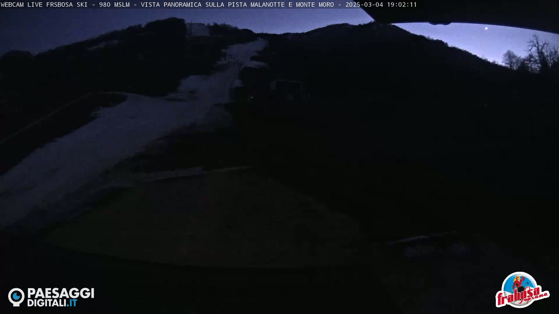 A dark, nighttime view of a snow-covered mountain slope under a twilight sky.