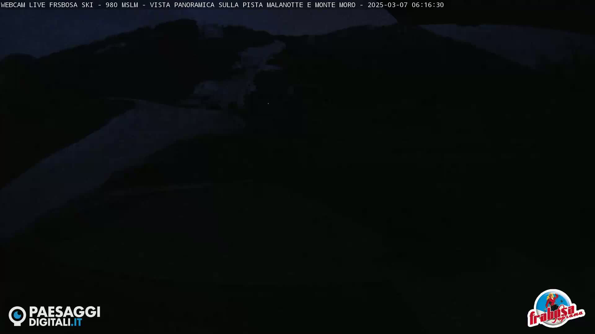 A dark, nighttime view of a snow-covered mountain slope.