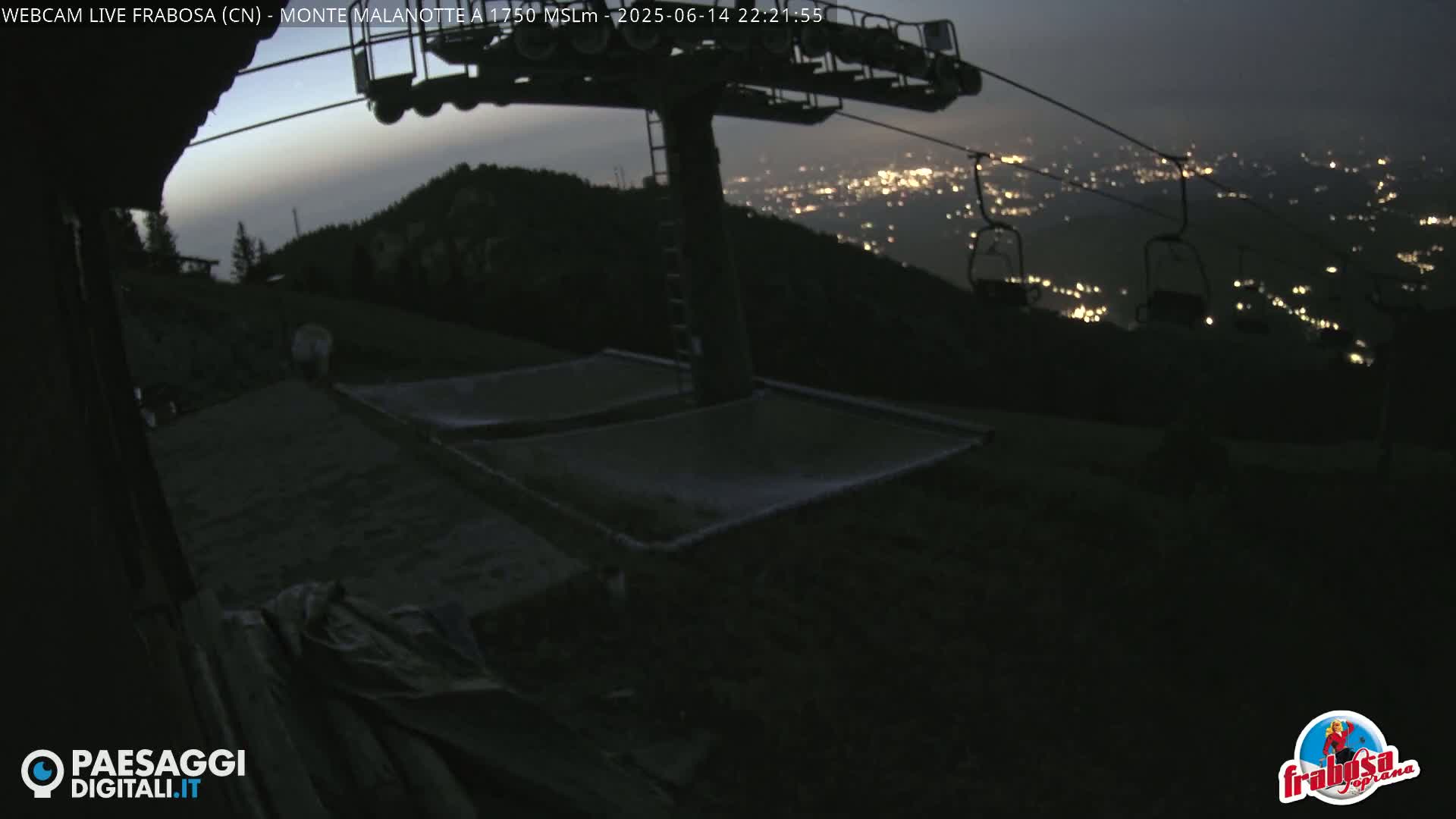 A mountaintop view shows an overcast sky, a chairlift, and two empty net hammocks near a building.
