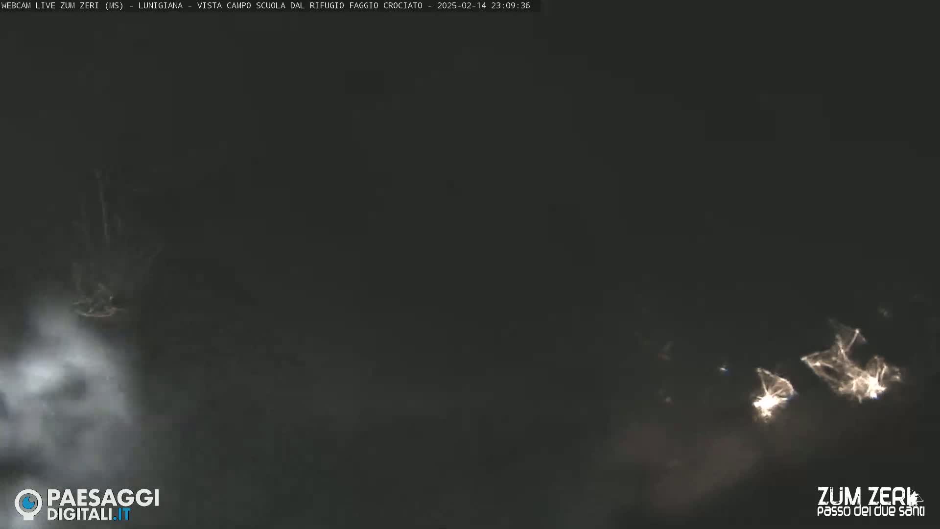 A nighttime, dark, and hazy scene shows faint lights in the distance.