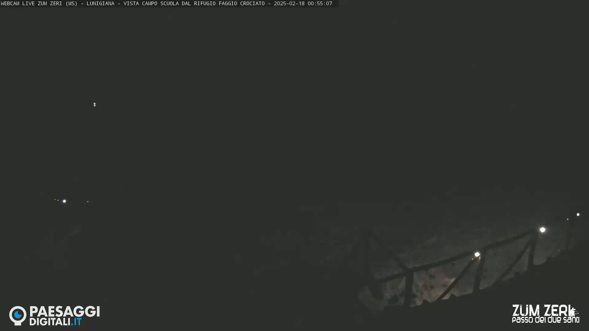 A nighttime, outdoor view shows a dimly lit railing descending into darkness.