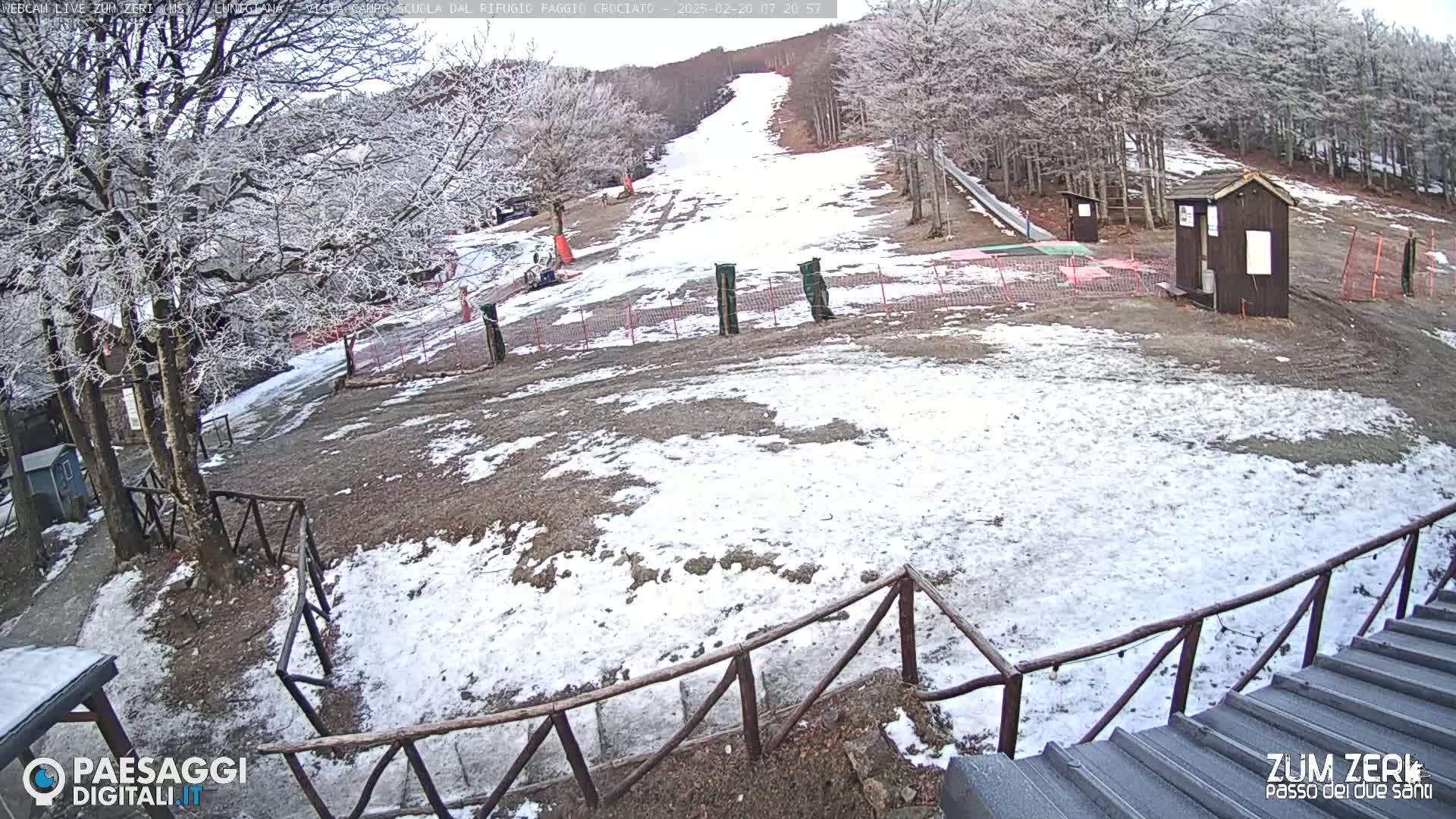 A snow-dusted ski slope is visible, surrounded by leafless trees in a wintry landscape.